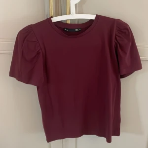 Vinröd topp med puffärm XS - Vinröd topp från H&M i storlek XS med korta puffärmar och rund halsringning. Tröjan är knappt använd!