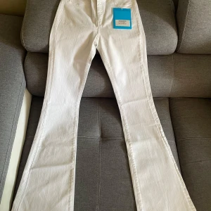 Vita jeans från M.i.h Jeans & Victoria Beckham - Två par vita jeans, ett från M.i.h Jeans med klassisk femficksdesign och bootcut-ben storlek 29, och ett från Victoria Beckham med croppad längd och uppvikta benslut storlek 26 passar 32. Båda i mjuk bomullsdenim, perfekta för en clean och fräsch look. Spliter nya etikett finns fortfarande kvar. Jeansen på bild 1 var för 2299kr säljs nu för 600kr. Bild nummer 2 var för 2399kr nu för 700kr