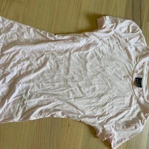 Ljusrosa basic t-shirt - Enkel och mjuk ljusrosa t-shirt. Klassisk rund halsringning och korta ärmar, perfekt till jeans eller shorts. Tillverkad i tunn bomull som känns skön mot huden. Snygg att styla lager på lager eller bara som den är.                                    Passform: tight