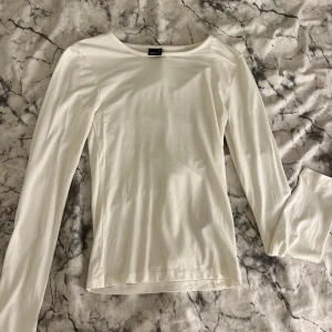 långärmad tröja  - En stilren och basic vit långärmad tröja från Gina Tricot. Tröjan har en rund halsringning och är tillverkad i mjuk bomull, perfekt att matcha med jeans eller kjol. Enkel design utan mönster eller detaljer, passar till många olika looks.