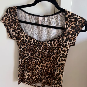 Leopardmönstrad topp från - Snygg leopardmönstrad topp med korta ärmar och rundad halsringning. Tunn och lätt i materialet, perfekt för att sticka ut lite extra. Färgerna går i beige, brun och svart för en riktigt trendig look.