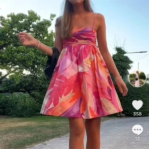 Färgglad kort sommarklänning - !!ÄR INTE HEMMA FÖRRÄN 7 JULI SÅ TRYCK EJ PÅ KÖP NU!! Superfin kort klänning med tunna axelband och färgstarkt abstrakt mönster i rosa, orange, lila och beige toner. Klänningen har en utsvängd kjol och figurnära liv, perfekt för varma dagar. Materialet känns lätt och luftigt.