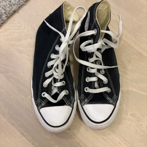 Svarta Converse - Klassiska svarta Converse All Star high-top sneakers med vit tå och sula, vita snören och tydliga kontrastsömmar. Logga på sidan och slitstark gummisula.