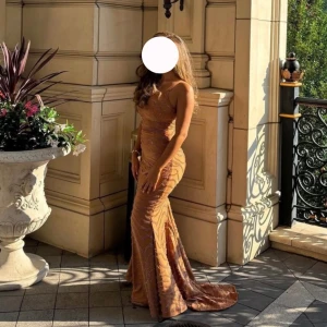 Karamellfärgad långklänning oh polly - Supersnygg karamellfärgad långklänning med smala axelband och figurnära passform. Klänningen har ett glittrigt mönster, vilket gör den perfekt för bal eller festliga tillfällen. Köpt för 2500kr + frakt i strl 8 och använd vid ett tillfälle. Skriv privat för frågor och fler bilder. 💕