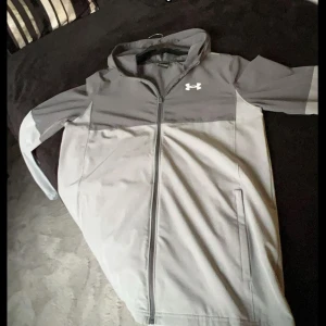  Under Armour vindjacka tunnjacka s barn XL - Storlek barn XL passar även S och XS Snygg tvåfärgad grå vindjacka från Under Armour. Använd 1 gång 