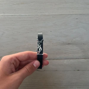 Saint Laurent armband  - Skick: 9/10 (så gått som nytt)                                        Färg: Svart                                                                       Og: Nej endast armbandet medföljer vid köp.           Äkta: Armbandet är 100% då det gått igenom en äktahets kontroll (bild bevis skickas privat)                 Size: One size                                                                    Vid fler frågor är det bara att höra av sig🤝                        // Doggelangelo   