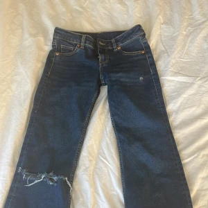 Blå flare jeans från hm - snygga utsvängda lågmidjade  jeans från H&M. Säljer pga att jag inte använt dom på ett tag. använde dom inte särskilt mycket förut heller kanske max 10 gånger. Väldigt bra skick, hålet är gjort själv!💘 passar mig i längden som är 167 så skulle säga passar bra på folk runt 165-170! Storlek 32/XS🥰