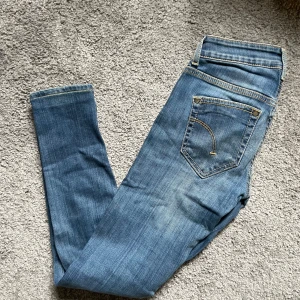 Blå slim  jeans från Dondup - Snygga blå slim jeans från Dondup med klassiska fem fickor och gul kontrastsöm. Jeansen har låg midja och är tillverkade i mjukt denimtyg som sitter tajt längs benen. Perfekta för dig som gillar en slimmad look.