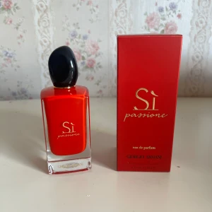 Giorgio Armani Sì Passione EdP 100ml - Giorgio Armani Sì Passione Eau de Parfum i en snygg röd glasflaska med svart lock och gulddetaljer. Flaskan rymmer 100 ml och kommer med matchande röd kartong. En ikonisk doft med elegant och modern design, perfekt för dig som gillar lyxiga parfymer.