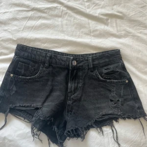 Svarta jeansshorts från Zara - Svarta jeansshorts från Zara med råa, fransiga kanter och slitna detaljer framtill. 
