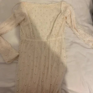 Oh polly klänning, går att pruta! - Superfin långklänning i vit nyans, täckt av pärlor för en lyxig känsla. Klänningen har lång ärm, figurnära passform och en snygg slits på sidan. Materialet är lätt och skimrande, perfekt för dig som vill sticka ut. Rund halsringning och dragkedja i ryggen. Använd 1 gång, size 8 vilket är S/M, maxi klänning är lång också jag är ca 175.