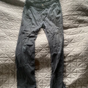 Svarta chinos från 157, storlek M - Svarta chinos från 157 i storlek M. Klassisk modell med snedställda fickor fram och två bakfickor. Byxorna har bälteshällor och stängs med knapp och dragkedja. Perfekta för en clean och enkel look.