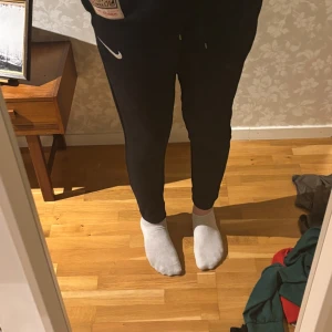 Svarta mjukisbyxor från Nike M - Svarta mjukisbyxor från Nike i storlek M. Byxorna har en slim passform med dragsko i midjan och klassisk Nike-logga på låret. Perfekta för chill eller träning, riktigt sköna och stilrena.