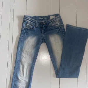 Lowrise crazy age jeans - Skitsnygga blå jeans från Crazy Age, lågmidjade och bootcut. Coolt tryck på rumpan (väldigt 2000 tal) något små i storleken, skriv för mått!