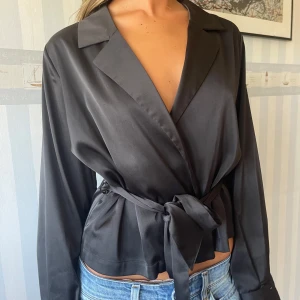 Svart silkes knytblus  - Samma modell som den rosa men en storlek större och i svart. Den går att knyta så tajt man vill så skulle passa alla. Ser super  elegant och dyr ut vilket jag älskar med den  
