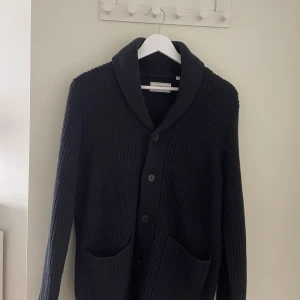 Blå stickad kofta från Produkt - Mysig blå stickad kofta från Produkt med bred krage, stora framfickor och knappar framtill. Perfekt för lager-på-lager och chill vibes. Klassisk modell med lång ärm och grovstickad struktur som ger en snygg och avslappnad look. Fick den som julklapp men vill sälja den nu. Priset kan diskuteras.