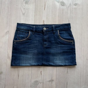 Mörkblå lågmidjad jeanskjol  - Blå jeanskjol från Zero i fint skick. Storlek 38 och passar S/M. Tvärs över midjan är det 39 cm + stretch och den är ca 30 sm lång (längs med sidan). Använd gärna köp nu!