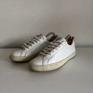 Veka sneakers - Stilrena vita sneakers från Veja med klassisk låg profil | Storlek: 38 | Perfekta skor för Svergies soliga och regniga dar | Defekt i hälen på skon förekommer ( bild 5 ), dessutom har gummisulan torkat ihop.