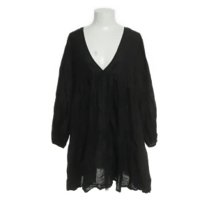 Svart luftig kortklänning med v-ringning - Svart kortklänning i luftig bomull med v-ringad hals och långa, voluminösa ärmar. Klänningen har en lös passform och faller snyggt med lätt rynkade partier. Perfekt för dig som gillar en avslappnad och trendig stil.