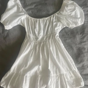 Vit kort klänning med puffärmar - Superfin vit kort klänning med puffiga kortärmar och söt knytning i ryggen.💞🤍storlek M men skulle säga att den mer är som S