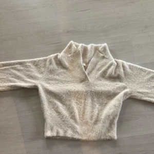 Beige fluffig stickad tröja H&M - Supermjuk och fluffig beige stickad tröja från H&M med hög krage och lång ärm. Perfekt för dig som gillar en cozy vibe och vill ha något som känns extra mysigt. Tröjan har en lätt oversized känsla och är enkel att styla till jeans eller kjol.