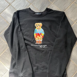  Polo Ralph Lauren sweatshirt - Svart tröja från Polo Ralph Lauren med ikoniskt Polo Bear-tryck framtill. Tröjan är i bomull, har rund hals och långa ärmar. Självklart äkta✅ Nypris:1800kr⁉️Vårt pris:500💸✅10/10 skick Priset är däremot inte hugget i sten. Hör av er vid minsta funderingar och frågor!😄