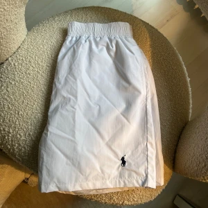 Vita shorts från Polo Ralph Lauren - Snygga vita badshorts från Polo Ralph Lauren med elastisk midja och innerbyxa i mesh. Fin färg som passar perfekt till sommaren. Skick-9:10. Storlek:-L men passar mer som M. DMa🤙