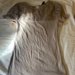 Beige spetsblus från H&M  - Supersöt beige blus från H&M i storlek XS. Toppen har korta ärmar och en överdel i vacker spets som ger en romantisk vibe. Mjuk och lätt i materialet, perfekt till jeans eller kjol. Rund halsringning och diskret enfärgad design.