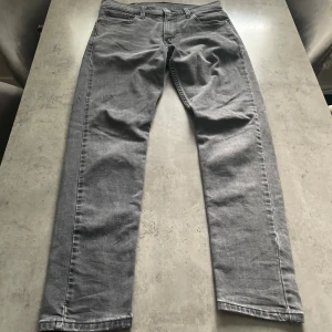 Grå Levi's 512 jeans straight fit - Snygga grå Levi's 512 jeans med klassisk femficksdesign och rakt snitt. Jeansen har en diskret tvättad look, normal passform och är tillverkade i mjukt bomullsjeans. Perfekta för dig som gillar stilrena och tidlösa jeans med en modern touch.