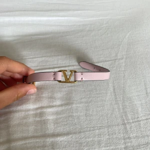 Valentino rosa läderarmband med guld V - Supersnyggt armband från Valentino garavani i ljusrosa läder med ikoniskt V-spänne i guld. Justerbart med guldfärgat spänne och diskret logga. Perfekt accessoar för att lyfta din outfit med en lyxig touch. I äkta kalvskinn. Superfint skick, säljer då jag sparar till mina dröm skor. Nypris 2715