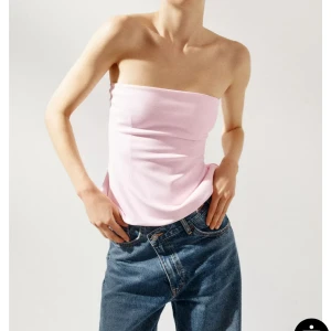 Ljusrosa bandeau tubtopp - Säljer en ljusrosa bandeau tubtopp med enkel och clean design. Toppen är axelbandslös och sitter tight över överkroppen. Perfekt att styla med jeans eller kjol för en trendig look. Mjuk och stretchig känsla. Aldrig andvänd 