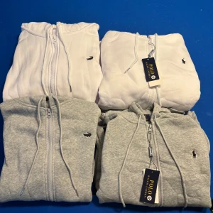 Grå hoodie från Polo Ralph Lauren - Helt nya aldrig använda. 600 kr för Lacoste och 750kr för polo. Snygg grå hoodie från Polo Ralph Lauren och Lacoste med dragkedja, huva och snörning. Klassisk logga broderad på bröstet och känguruficka framtill. Perfekt för en chill och avslappnad stil. Tillverkad i mjuk bomullsmix som känns skön mot huden.
