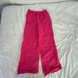 Rosa linnebyxor med snörning - Snygga och chill rosa linnebyxor med breda ben och elastisk midja med snörning. Perfekta för varma dagar när du vill ha något luftigt och bekvämt. Färgen är riktigt poppig och materialet är lätt och svalt.