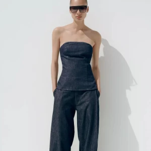 Mörkblå jeans bandeau topp - Säljer en stilren mörkblå bandeau topp i jeansmaterial. Toppen är axelbandslös och har en figurnära passform som ger en clean och modern look. Perfekt att matcha med både jeans och vida byxor för en cool denim-on-denim vibe.