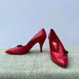 Libra Shoes Klackar - Snygga högklackade skor från Libra Shoes i storlek 36. Djärv röd färg med en svart detalj på den främre yttre sidan som ger skon en lekfull och unik touch. Skorna är i mycket bra skick och sparsamt använda. Perfekta för fest, middagar eller tillfällen då du vill sticka ut med stil och elegans.