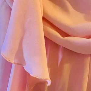 Rosa Jumpsuit med rosettdetalj, strl 40  - Säljer en ljusrosa jumpsuit i flowigt polyestertyg. En snygg rosettdetalj framtill ger en festlig vibe. Materialet är mjukt och ger ett elegant intryck. Perfekt för dig som gillar en feminin och trendig look.