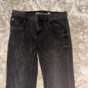 Svarta straight jeans från LAB Industries - Snygga svarta jeans från LAB Industries med klassisk femficksdesign och raka ben. Jeansen är tillverkade i mjukt denim och har en mörk tvätt som ger en cool vibe. Passar perfekt till sneakers. Dock finns ett litet hål i skrevet men går att fixa innan postning 
