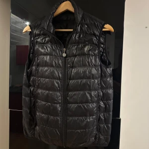 Svart dunväst från EA7 Emporio Armani - Snygg svart dunväst från EA7 Emporio Armani i storlek S. Västen säljs pga den ej passar min stil längre. 