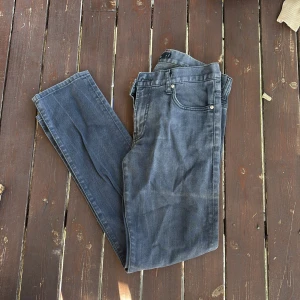 Grå jeans från J.Lindeberg, 33/32 - Säljer ett par snygga grå jeans från J.Lindeberg med klassisk femficksdesign och diskret logga på bakfickan. Jeansen har raka ben och är tillverkade i mjukt bomullstyg med lite stretch för extra komfort. Perfekta för en clean och stilren look.