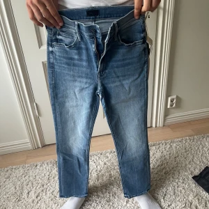 Blå jeans från Mother, storlek 25 - Snygga blå jeans från Mother i klassisk tvätt med raka ben och normal passform. Jeansen har fem fickor, dragkedja och knapp framtill samt diskret logga på bakfickan. Perfekta för dig som gillar en enkel och stilren look.