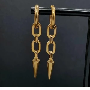 Guldiga kedjeörhängen med spets - Snygga örhängen i guldton med kedjelänkar och spetsig konformad detalj längst ner. De har en modern och edgy vibe, perfekta för att lyfta din stil. Hängande modell som ger ett coolt statement till din look.