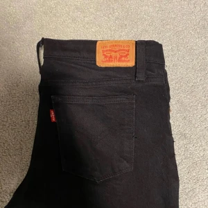 Levi's 501 - Säljer ett par klassiska svarta Levi's 501 jeans storlek 14A. Byxorna har raka ben men sitter mer slim än vanliga 501or. fem fickor och den ikoniska läderpatchen bak. Passar perfekt till dig som gillar tidlös stil och vill ha ett par jeans som funkar till allt.