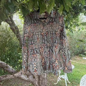 Mönstrad långärmad skjorta Odd Molly - Säljer en unik långärmad skjorta från Odd Molly med ett färgstarkt och detaljerat mönster i svart, orange, beige och turkos. Skjortan har klassisk krage, knappar framtill och är tillverkad i mjuk bomull. Perfekt för dig som gillar att sticka ut med coola prints. Storlek 2 som enligt deras storleksguide motsvarar en storlek M.  Mycket fint skick, jag hittar inga synliga anmärkningar eller defekter.