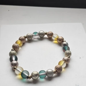 Färgglatt pärlarmband med metallic - Unikt armband med pärlor i silver, guld, grönt och gult. Vissa pärlor är glittriga och andra har en matt finish, vilket ger en cool mixad look. Elastiskt band gör det enkelt att ta på och av. 