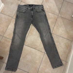 Replay Hyperflex Anbass grå jeans - Replay Hyperflex Anbass jeans i snygg grå tvätt. Modellen har smal passform och stretchigt material som gör dem riktigt sköna. Diskreta Replay-detaljer på fickorna. Använda ett fåtal gånger.