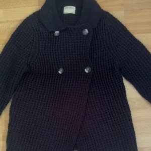 Svart stickad cardigan kofta Zara - Mysig marinblå stickad cardigan kofta från Zara Girl’s Winter Collection. Kofta har dubbelknäppning med stora knappar och en bred krage. Grovstickad struktur som ger en cool och avslappnad vibe. Perfekt för kalla dagar när du vill vara både varm och snygg. Kan bäras  på två sätt, titta på bilder. Storlek 152cm, men det kan passa xs också.