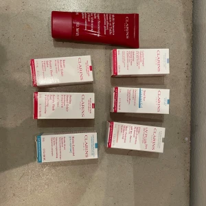 Clarins ansiktsprodukter kit - Säljer ett kit med flera ansiktsprodukter från Clarins, bland annat primer, face mist och toner. Produkterna kommer i vita och röda förpackningar och är perfekta för dig som vill ha en fräsch och återfuktad bas innan smink. Allt är i smidiga tuber och flaskor, lätt att ta med.