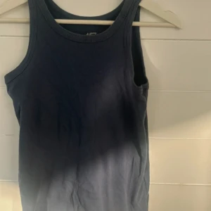 Mörkblå ribbad linnetopp från 157 - En enkel och stilren mörkblå linnetopp från 157 i 100% bomull. Toppen är ribbad och har breda axelband och rund halsringning. Perfekt att matcha med jeans eller shorts för en avslappnad look.