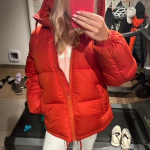 Röd fluffig jacka  - En röd puffig jacka till vintern. Påminner nästan lite om fjällräven jackan men inte helt. Den är i storlek XS men skulle säga att den är lite stor i storleken så passar även en S också. 