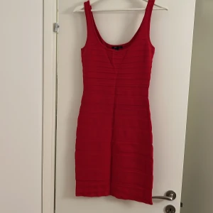Röd kort ärmlös klänning - Snygg röd klänning med kort längd och ärmlös design. Klänningen har en rundad halsringning och horisontella ribbade detaljer som ger en cool struktur. Perfekt för dig som vill sticka ut med en enkel men stilren look.